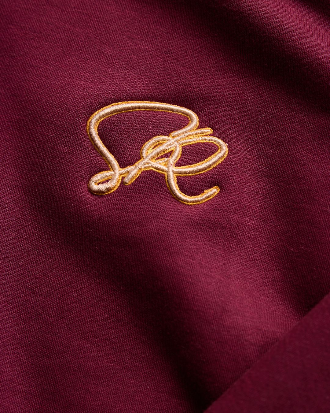 Close-up of a gold embroidered design on a burgundy fabric background