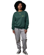 Person wearing a green sweatshirt and gray pants on a white background