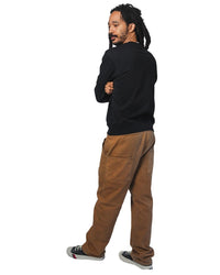 Man wearing a black crewneck and brown pants on a white background