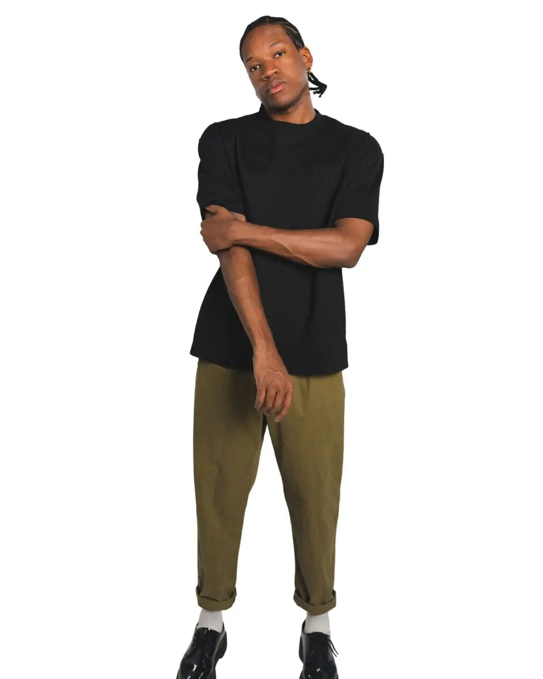 Person wearing a black streetwear shirt and green pants on a white background