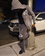 model wearing grey 90 tracksuit leaning against a lightpole