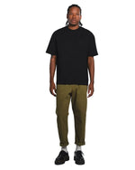 Person wearing a black core t-shirt and green pants on a white background