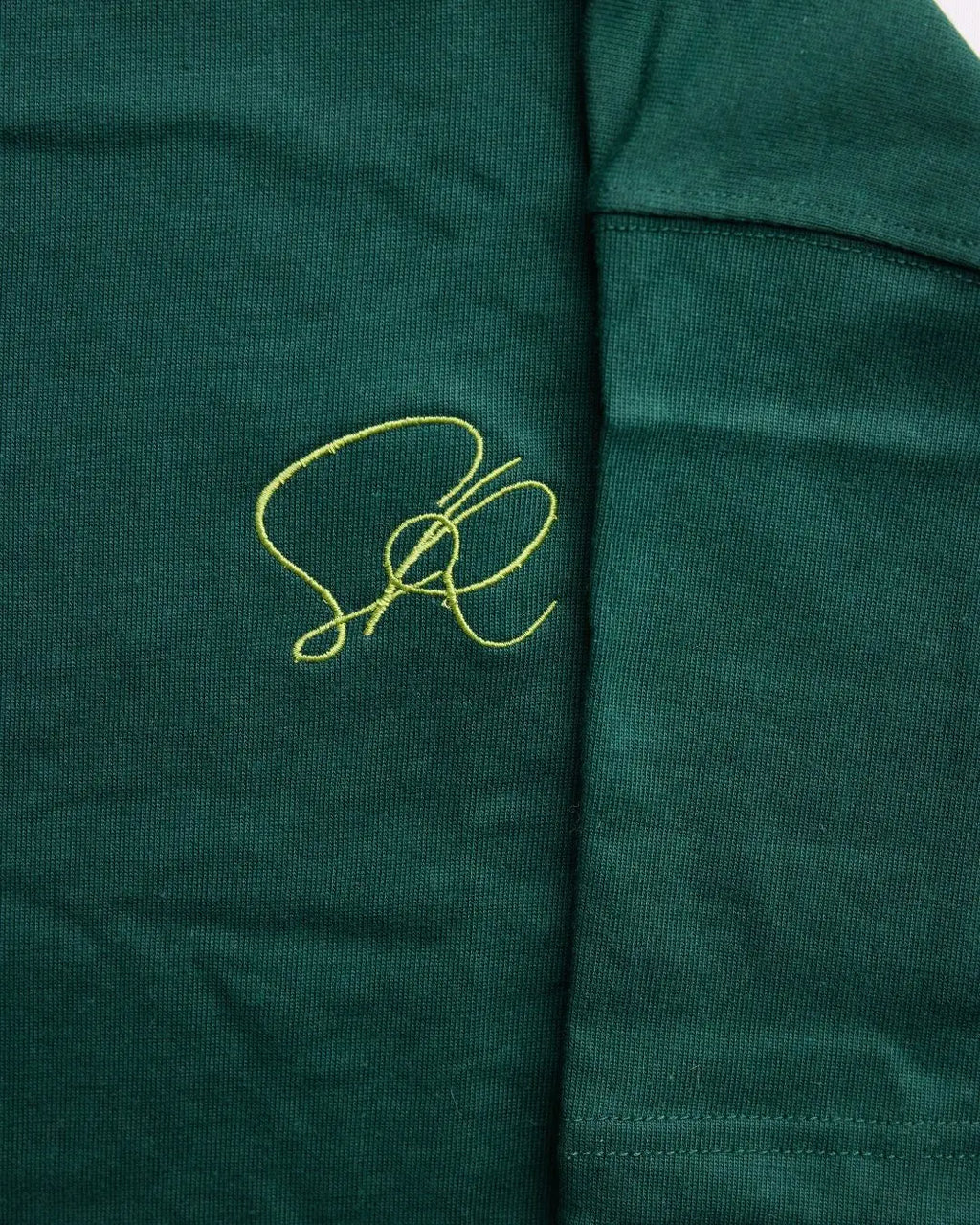 Close-up of shirt fabric with a green embroidered logo on a green background