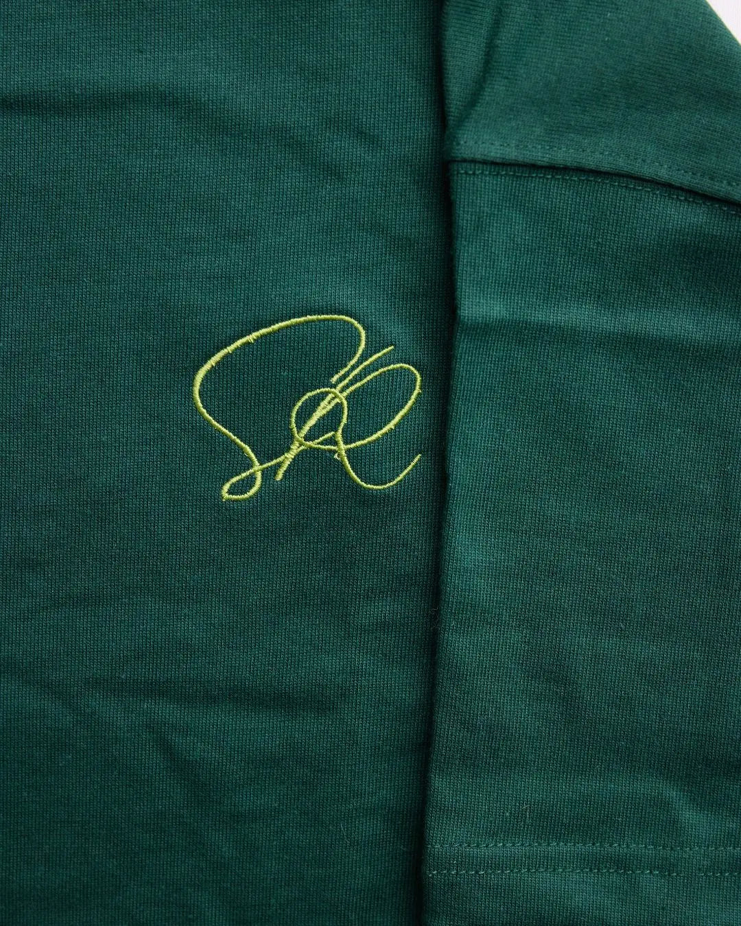 Close-up of shirt fabric with a green embroidered logo on a green background
