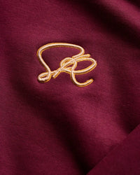 Close-up of a gold embroidered design on a crimson sweatshirt fabric background