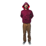 A person wearing a reversible hoodie with the hood on, showcasing a red the crimson side, paired with brown pants.
